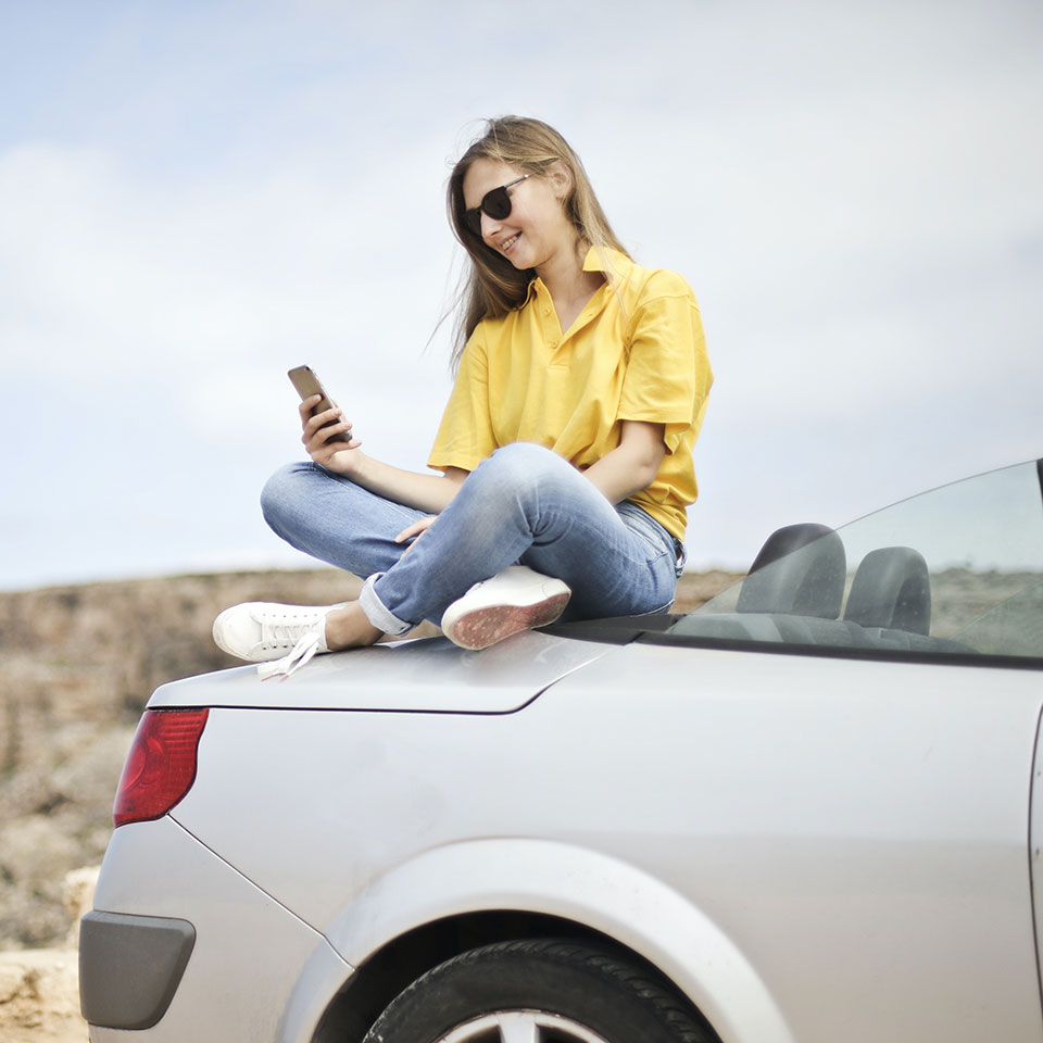 A woman on a car looking at her phone